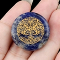 25mm blue lapis lazuli stone disc with gold tree of life engraving held in hand - Blue Sodalite