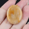 Pietra di cristallo giallo ovale lucida da 28 mm in mano con trama naturale - Giada Gialla