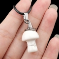 White marbled stone mushroom pendant necklace with a black braided cord on hand - Howlite