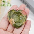 Unakite heart worry stone with green and pink patterns held in hand for healing - Unakite