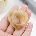 Polished natural citrine quartz worry stone in a smooth heart shape held in hand - Yellow Jade