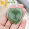 Polished heart-shaped green aventurine worry stone held in hand for healing - Green Aventurine