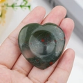 Polished heart-shaped bloodstone worry stone with red spots held in hand - African Blood Stone