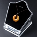 Polished yellow agate stone donut pendant necklace with brown braided cord on stand - Topaz