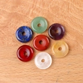 Set of 7 natural crystal chakra donut pendants in various colors on a wooden surface - Medium Donut Style (14mm)