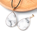 Water drop white marble pendant with golden plated bezel on a natural wooden tray - Howlite
