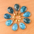 Set de 9 gemas azules facetadas en forma de gota con enganches dorados sobre madera - Apatita
