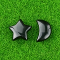 Polished black agate star and moon crystal set on a green decorative surface - Obsidian