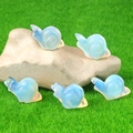 Mini-Schneckenfiguren aus Opalit-Kristall-Set auf Naturstein mit grünem Rasenhintergrund - Synthetischer Opal