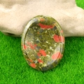 Polished unakite worry stone with natural green and pink patterns on grass - Unakite