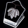 Carved grey agate maple leaf pendant necklace on a black velvet display stand - Grey Agate