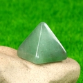 Green Aventurine pyramid energy stone on natural raw rock with garden background - Green Aventurine