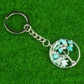 Light blue crystal tree of life keychain with silver wire wrap on green grass - Amazonite