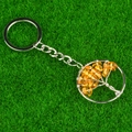 Tree of Life keychain with silver wire-wrapped yellow crystal stones on green grass - Dark Citrine