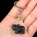 Hand-carved black obsidian elephant keychain with silver metal ring held in hand - Obsidian