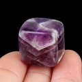 Handheld view of a 16mm polished purple crystal cube with natural V-shaped white patterns - Amethyst