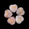 Five heart-shaped rose quartz stones with gold Strength engraving on black background - Strength (STRENGTH)