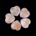 Natural rose quartz heart stones with golden Trust engraving on black background - Trust