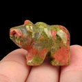 Unakite polar bear animal gemstone carving ornament held in hand on black backdrop - Unakite