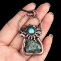 Vintage bronze sun necklace with turquoise and green crystal held in hand - Fluorite