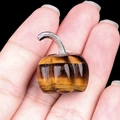 Mini pumpkin-shaped tiger eye stone carving with silver stem held in hand - Tiger's Eye