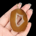 Large irregular brown agate slice pendant with gold plated rim held by hand - Yellow Agate (Gold Edge)