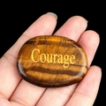 Polished tiger eye palm stone featuring golden Courage engraving in a hand - Courage (Tiger Eye Stone)