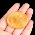 Pierre de paume en agate jaune naturelle ovale gravée Dream dorée tenue en main - Rêve (Jade Jaune)