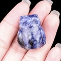 Miniature owl figurine carved from blue Sodalite stone shown held between fingers - Sodalite