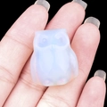 Mini opalite owl figurine carving held in hand with a high contrast black background - Opal (Synthetic)