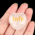 Pink rose quartz heart stone with golden INFP lettering held in hand on black background - Mediator/Infp