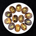 Set di 12 pietre occhio di tigre ovali con simboli zodiacali dorati incisi su fondo glitter - Occhio di tigre