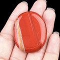 Polished red jasper worry stone with natural yellow veins held in palm for size - Red Jasper
