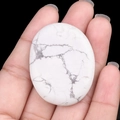 Oval white howlite worry stone with natural grey marble veins held in hand - Howlite
