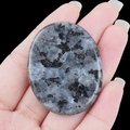 Handheld oval polished labradorite worry stone with natural blue schiller and dark mineral inclusions - Larvikite