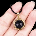 Golden hexagram pendant with black obsidian stone and black cord being held by a hand - Black Agate (Gold)