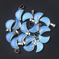 Light blue translucent moon pendants with silver metal clasps on black texture - Opal