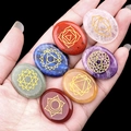 Set di sette pietre chakra naturali ovali levigate tenute nel palmo di una mano umana - Collezione di Pietre Energetiche Simbolo Chakra