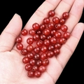 Hand holding polished red agate round beads for DIY jewelry making and crafting - 8mm Diameter 2mm Hole