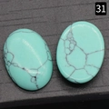 Twee ovale turquoise cabochons met natuurlijke aders op een zwarte achtergrond - Synthetisch Blauw Turkoois / 18x25mm