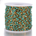 Detail of DIY golden stainless steel chain with blue enamel beads on a white spool - Gold-Blue