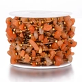 Close-up of orange crushed stones and gold beads on a spool for DIY jewelry making - Gold - Red