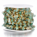 Detail of bohemian gold bead chain with green natural stone chips on white spool - Gold-Green