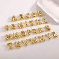 Macro shot of 26 puffed gold alphabet pendants arranged on a white textured surface - Full Set of 26 Alphabet Letters / Gold
