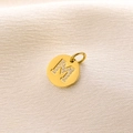 Luxury 14K gold circular pendant featuring crystal-encrusted letter M on white satin - Letter M