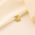 Pendentif lettre Z évidé en acier inoxydable doré sur fond élégant en soie beige - Lettre évidée Z