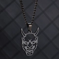 Vue macro du pendentif masque Hannya en acier inoxydable avec cornes et fini oxydé - Masque Noir Chaîne Gourmette