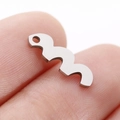Polished stainless steel irregular wave charm held on fingertip to show small scale - M-Shaped Wave (DY766-1)