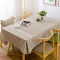 Detalle de mantel de cuadros beige con caída natural sobre una mesa de comedor de madera - 60x60cm / Cuadros Marrones
