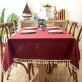 Close-up of deep red linen-textured tablecloth featuring elegant white tassel fringes - 120x160 / Tassel Style / Burgundy